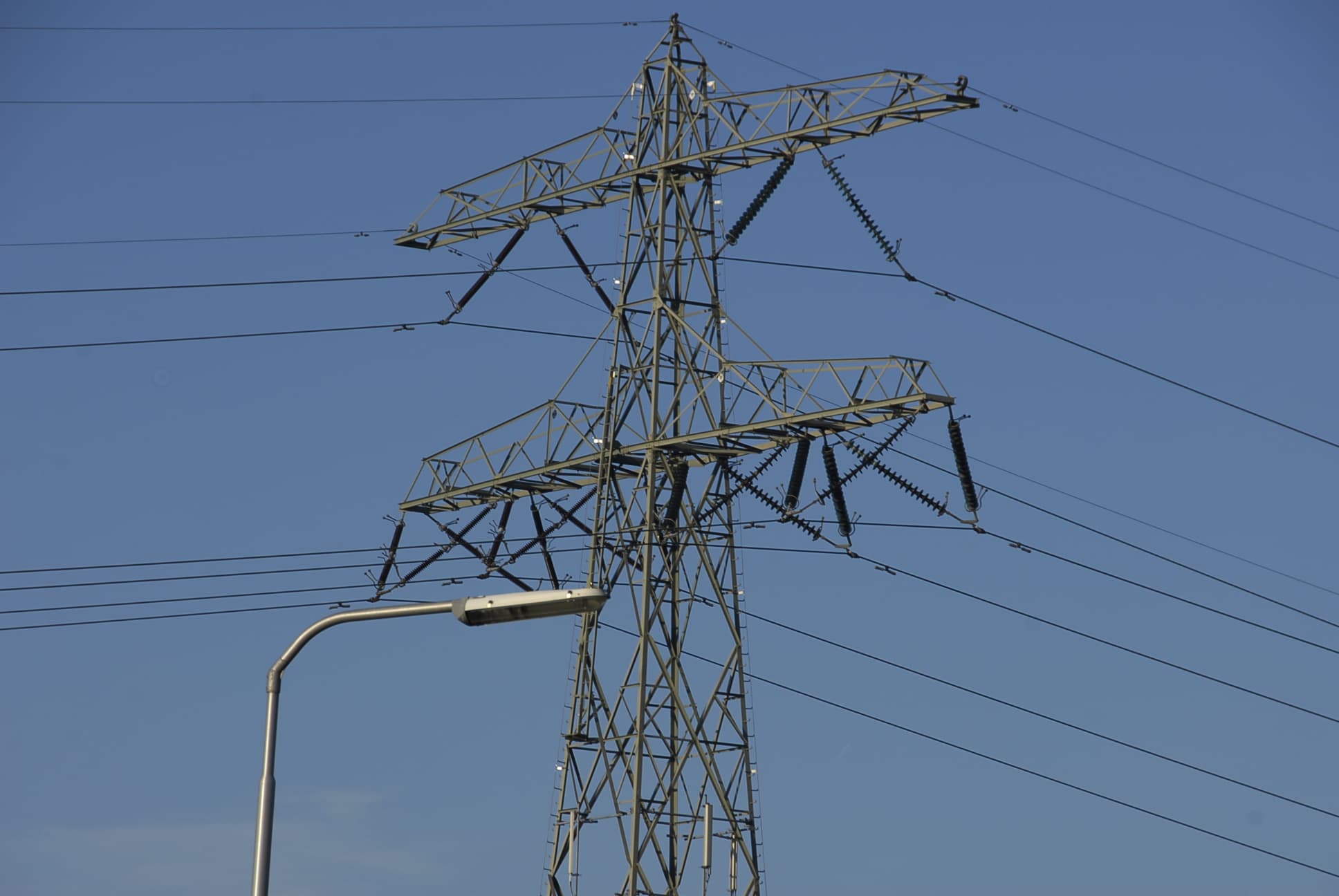 Hoogspanningsmast en openbare verlichting tegen een blauwe lucht